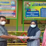 Teks foto : Kepala Sekolah SD N 110 Pekanbaru Menyerahkan Mukena Kepada Pihak Sekolah (foto/KEND ZAI).