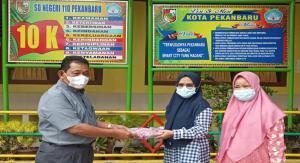 Teks foto : Kepala Sekolah SD N 110 Pekanbaru Menyerahkan Mukena Kepada Pihak Sekolah (foto/KEND ZAI).