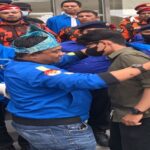 Teks foto : Haris Pertama memberikan baju KNPI sekaligus memasangkannya kepada dua orang koordinator lapangan massa aksi (Istimewa).